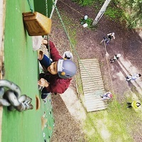 child ringing the bell at the top of the climbing wall